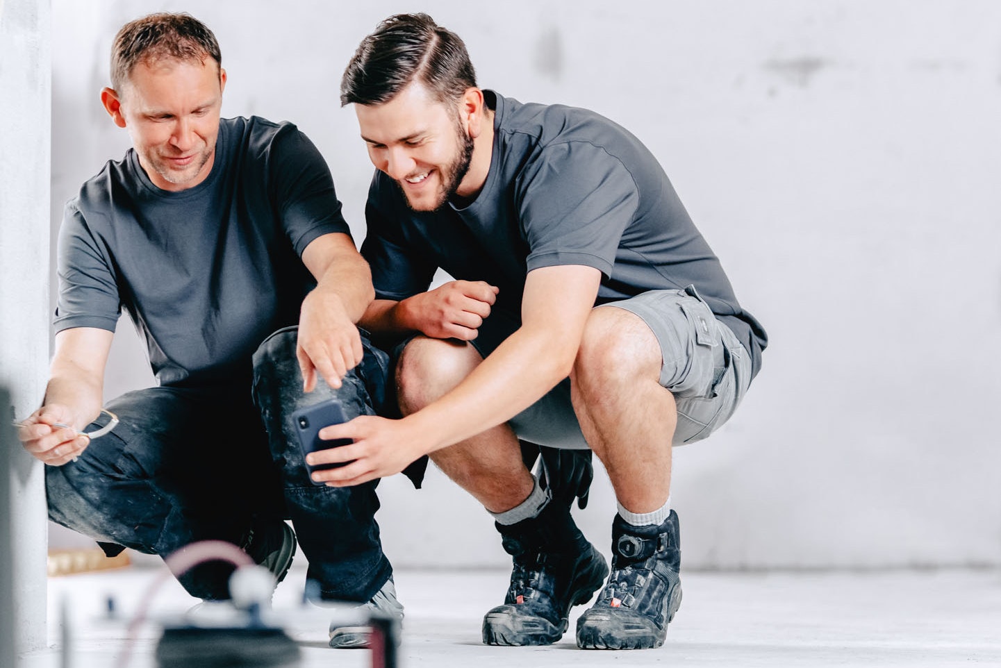 Two construction workers install cables while kneeling