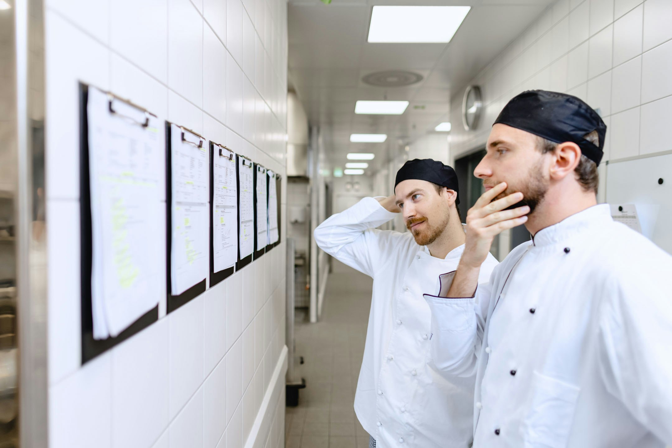 Two chefs are looking at the menu in the kitchen