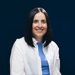 Porträt von Anna Radermacher in weißem Hemd vor einer dunkelblauen Wand