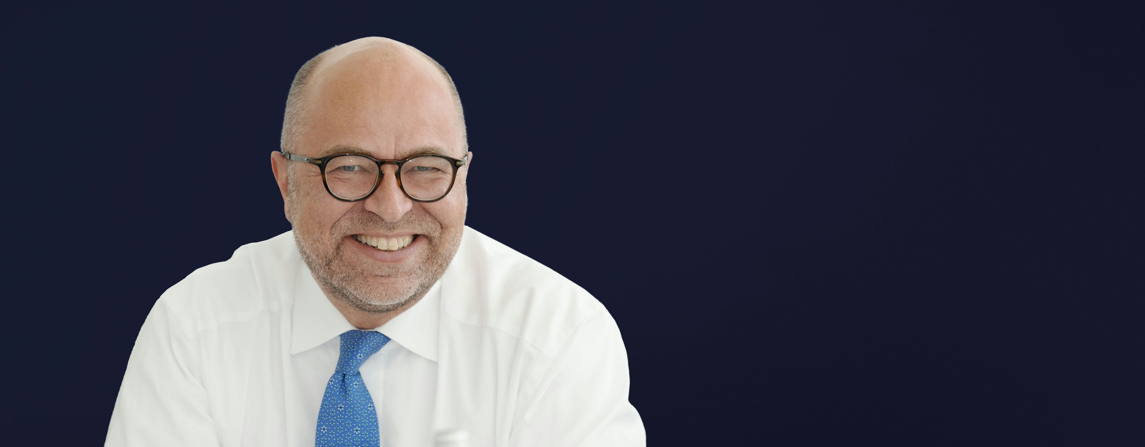 Stephan Rüschen is wearing a white shirt and a blue tie