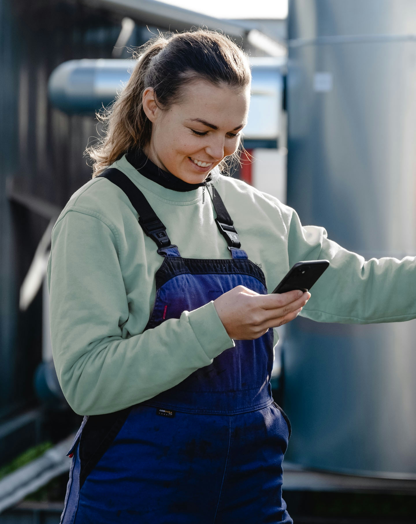 Brunette female maintenance worker in front of industrial plant