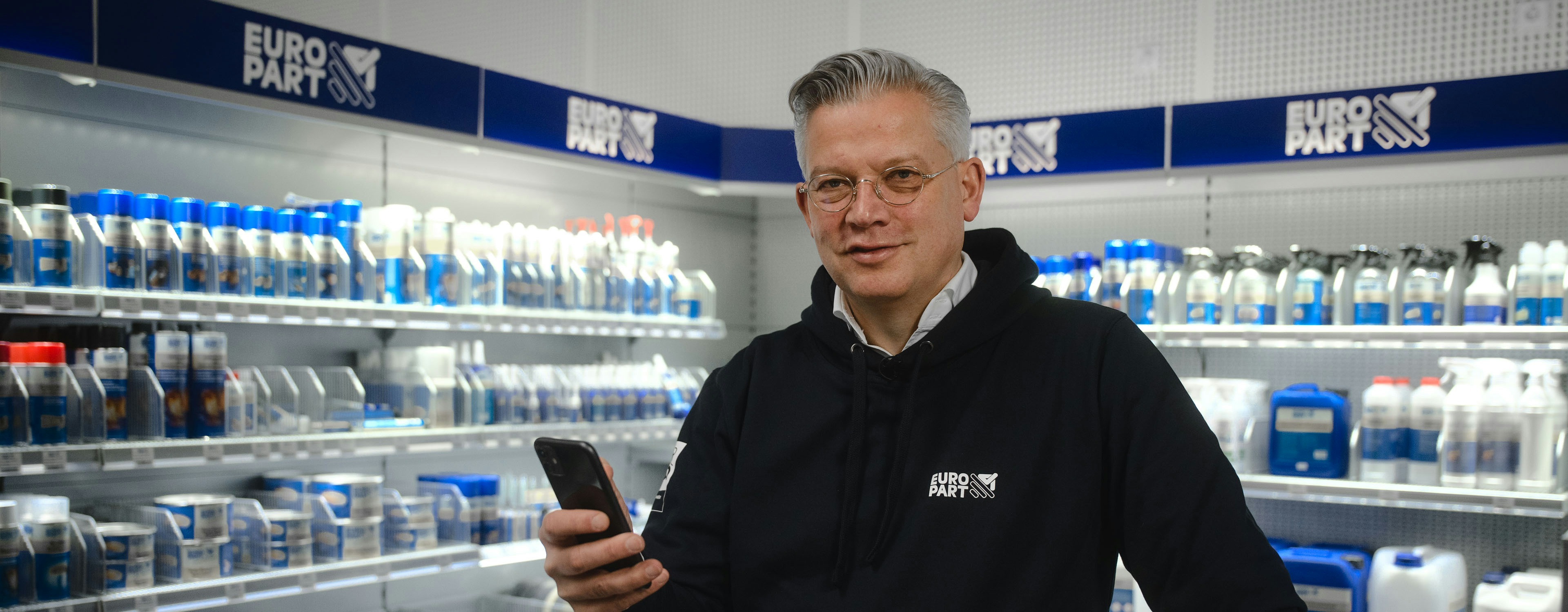 Olaf Giessen holding a smartphone in a Europart store