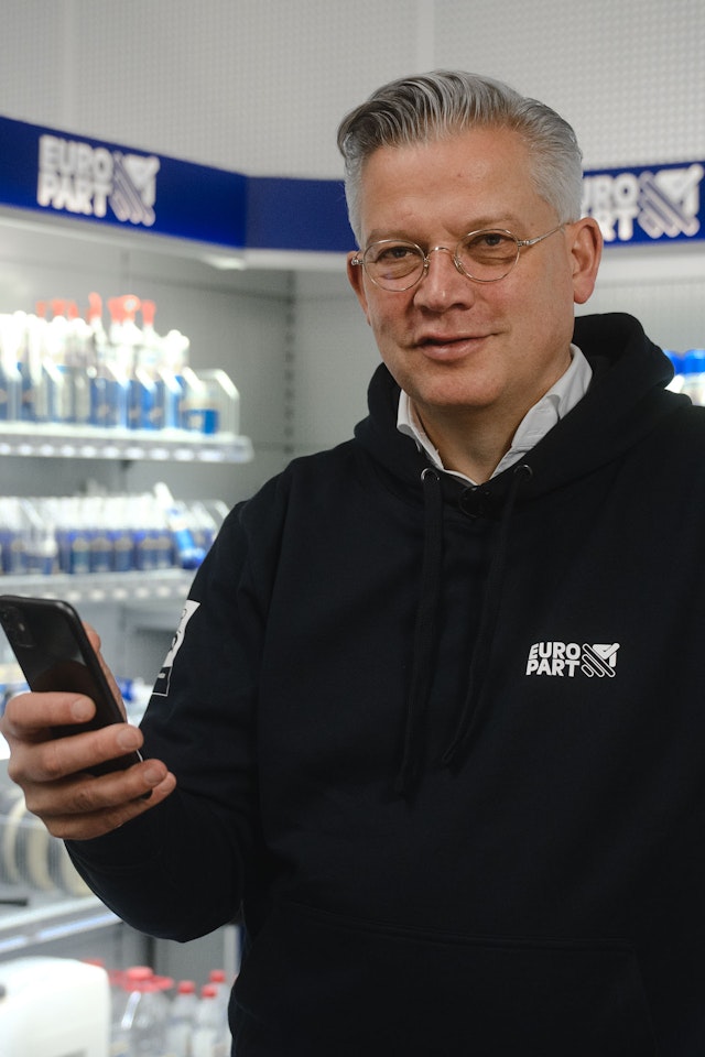 Olaf Giessen holding a smartphone in a Europart store