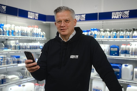 Olaf Giessen hält ein Smartphone uns steht in einer Europart-Filiale