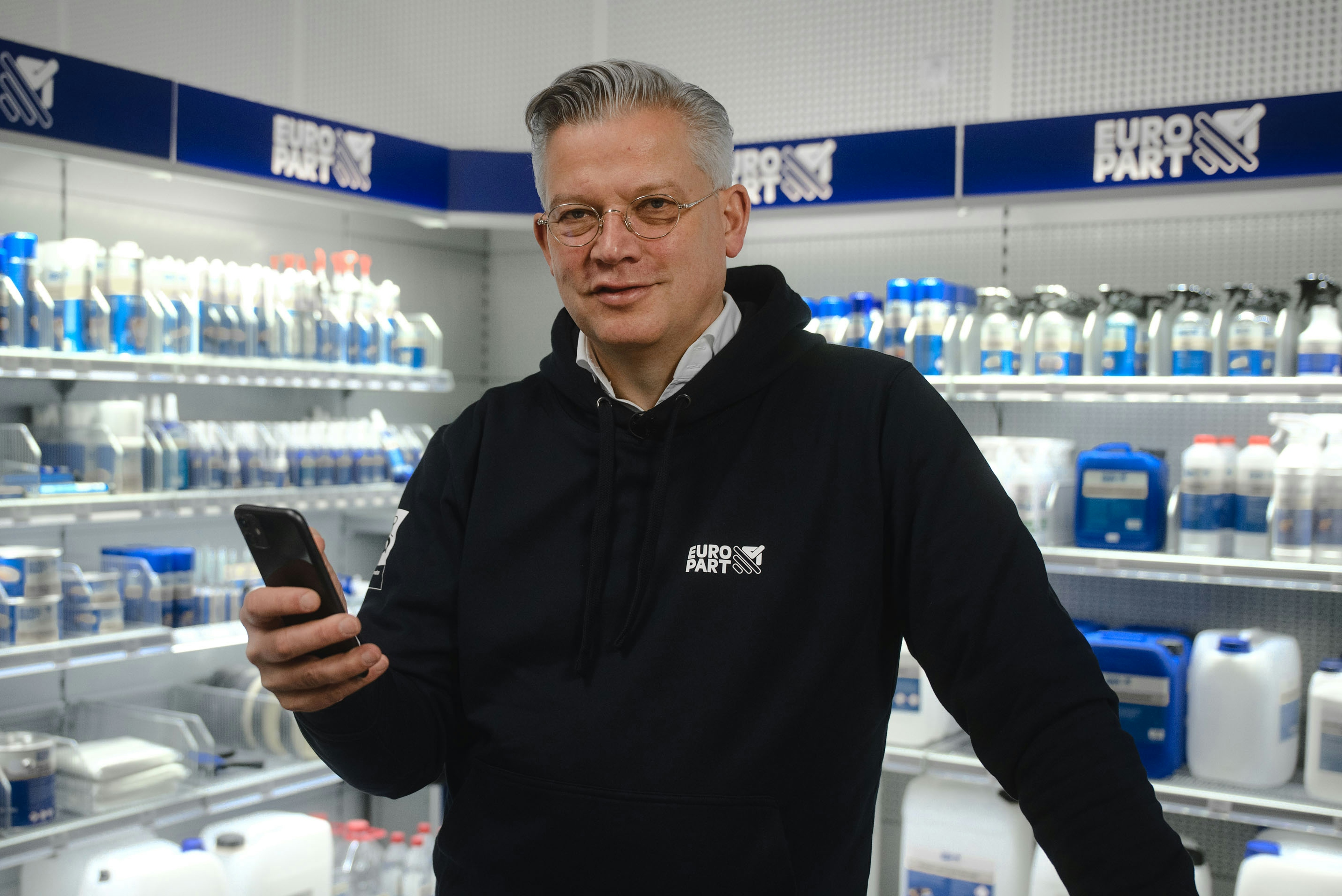 Olaf Giessen holding a smartphone in a Europart store