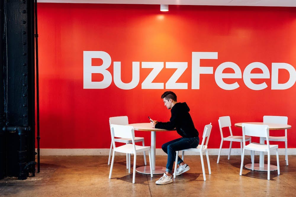 Person sitting at table near a wall with BuzzFeed logo