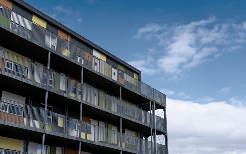 Íbúðabygging, blár himinn og hvít ský í bakgrunni