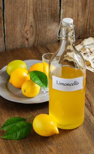 botella de limoncello casero con limones
