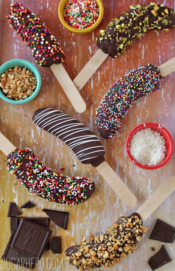 Plátanos bañados en chocolate con virutas de colores en una mesa