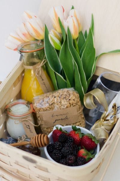 Cesta desayuno con zumo, muesli, fruta y flores