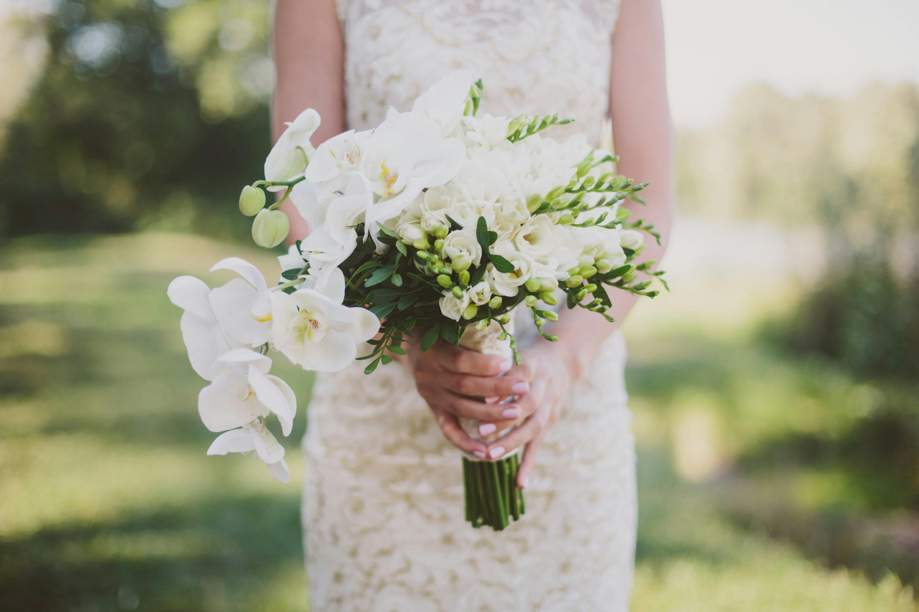 Novia con ramo blanco sobre fondo de campo