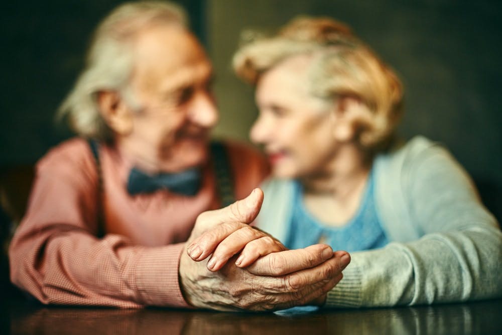 Un hombre y una mujer mayores se cogen de la mano