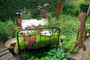 An old bed with a grass mattress and metal sculptures at the Picker garden in Borken-Weseke (Germany).