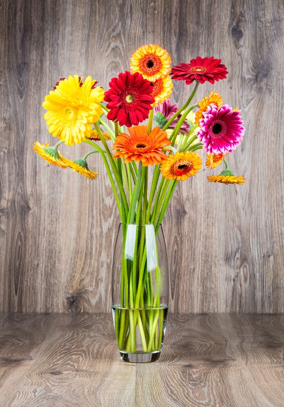 Bouquet of flowers in the vase on wooden background