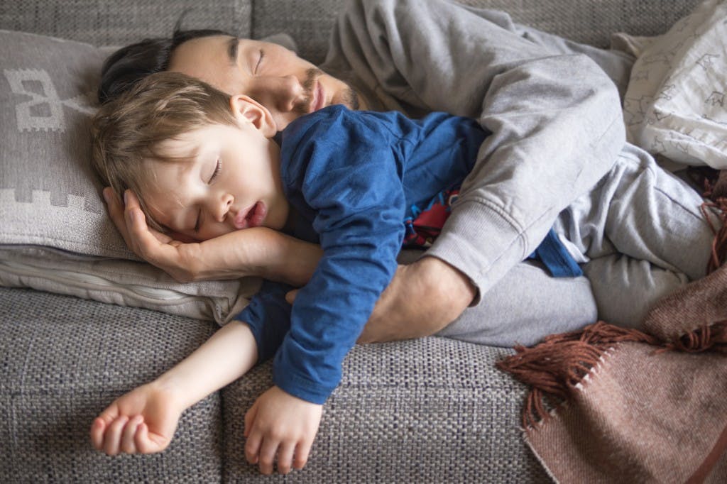 portrait of father and son fallen asleep together on the couch