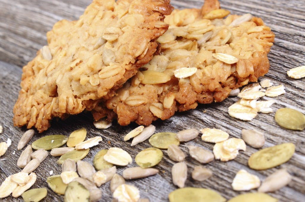 Homemade fresh baked oatmeal cookies with pumpkin and sunflower on wooden background, concept for healthy nutrition and dessert