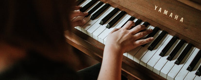 Frau spielt am braunen Yamaha Klavier