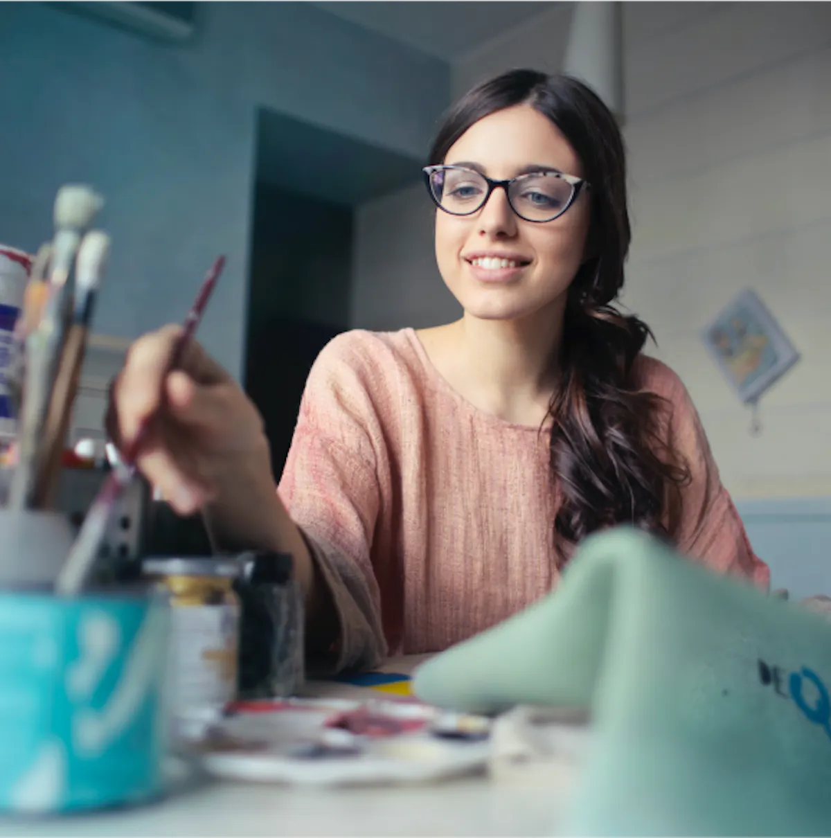 a smiling women in glasses painiting