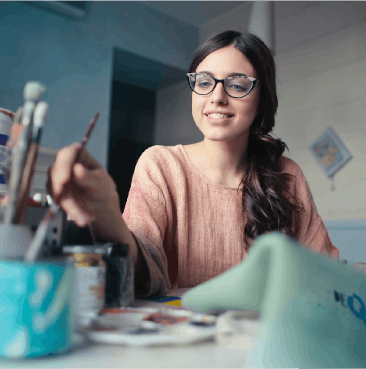 A smiling woman in glasses painting