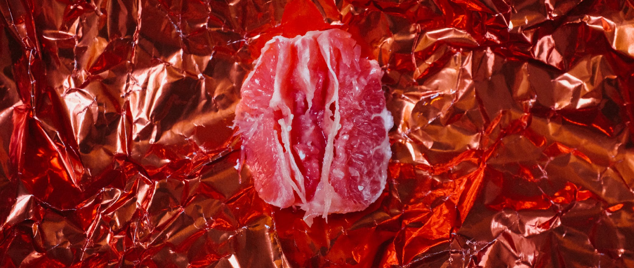 Crumbled red foil paper as the background with a slice of grapefruit kept on it