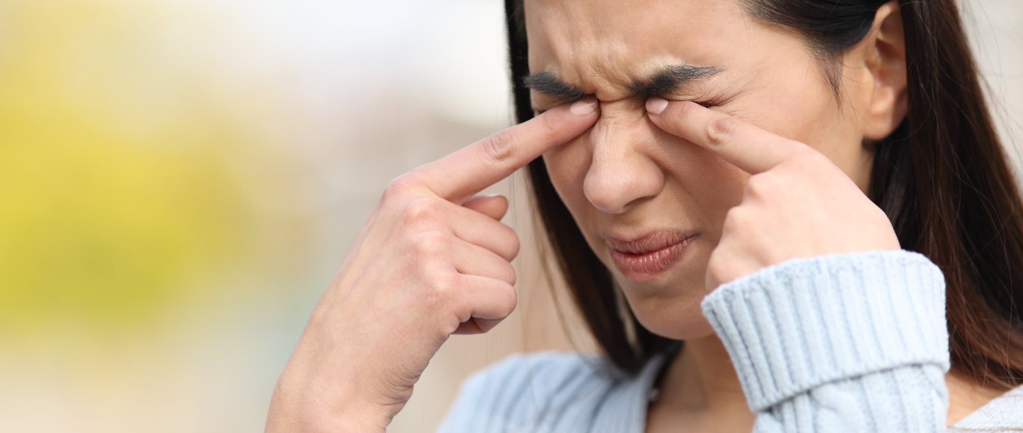 A woman rubbing her eyes due to irritation.