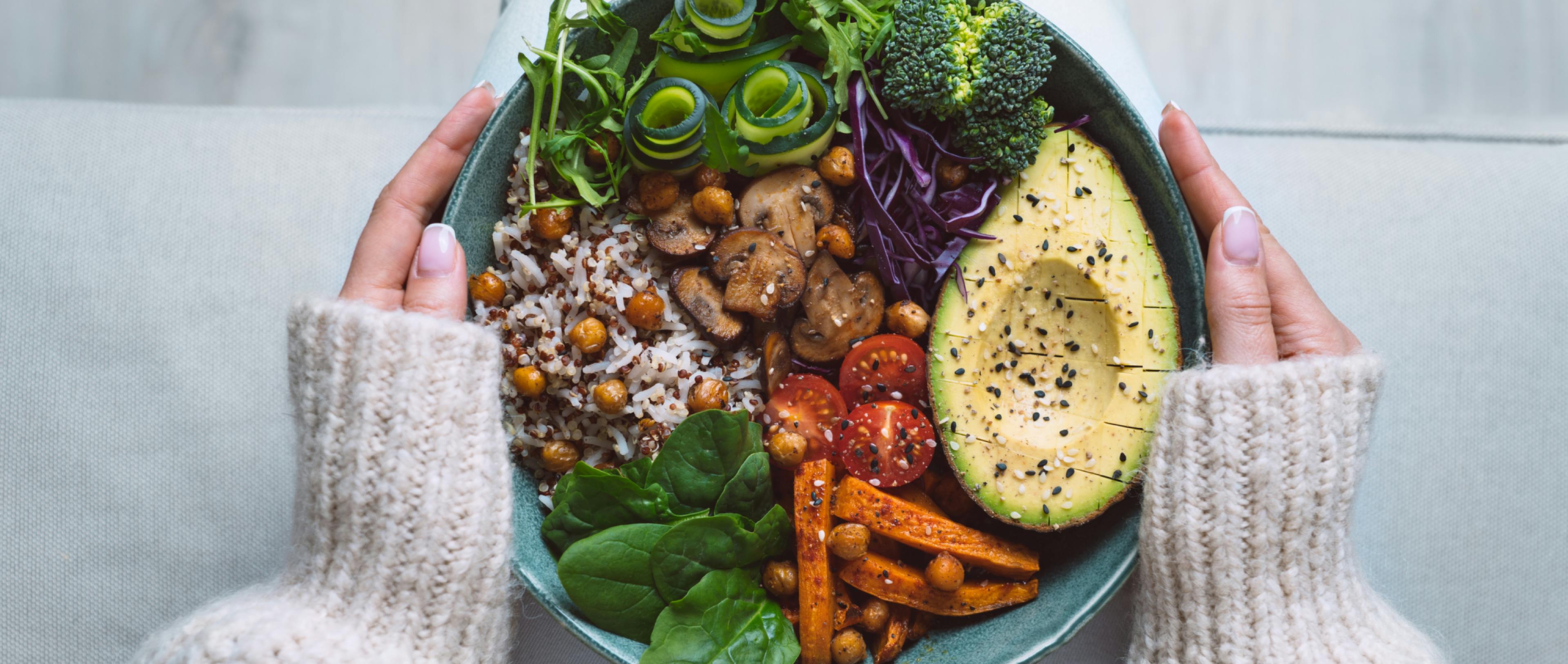 A woman holding a bowl of food full of protein. 