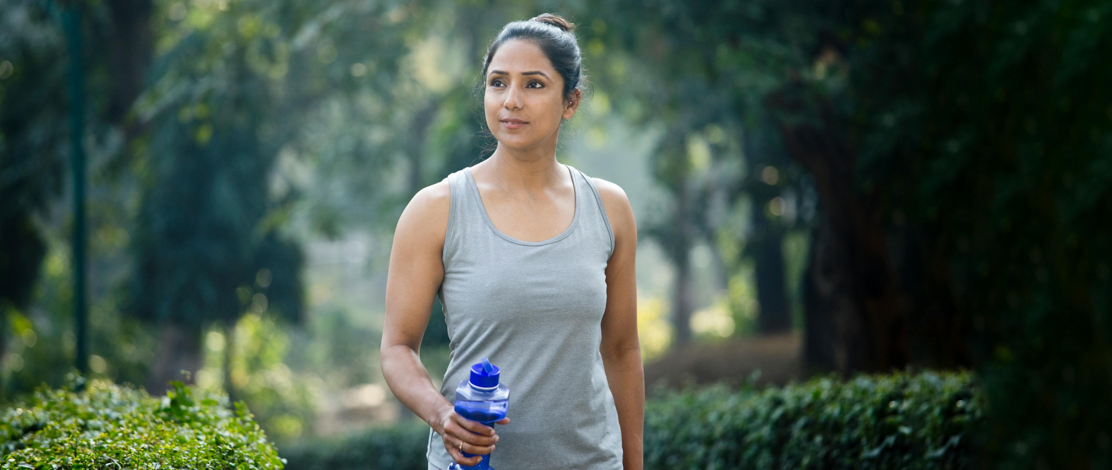 A woman walking with a water bottle shaped like a dumbbell