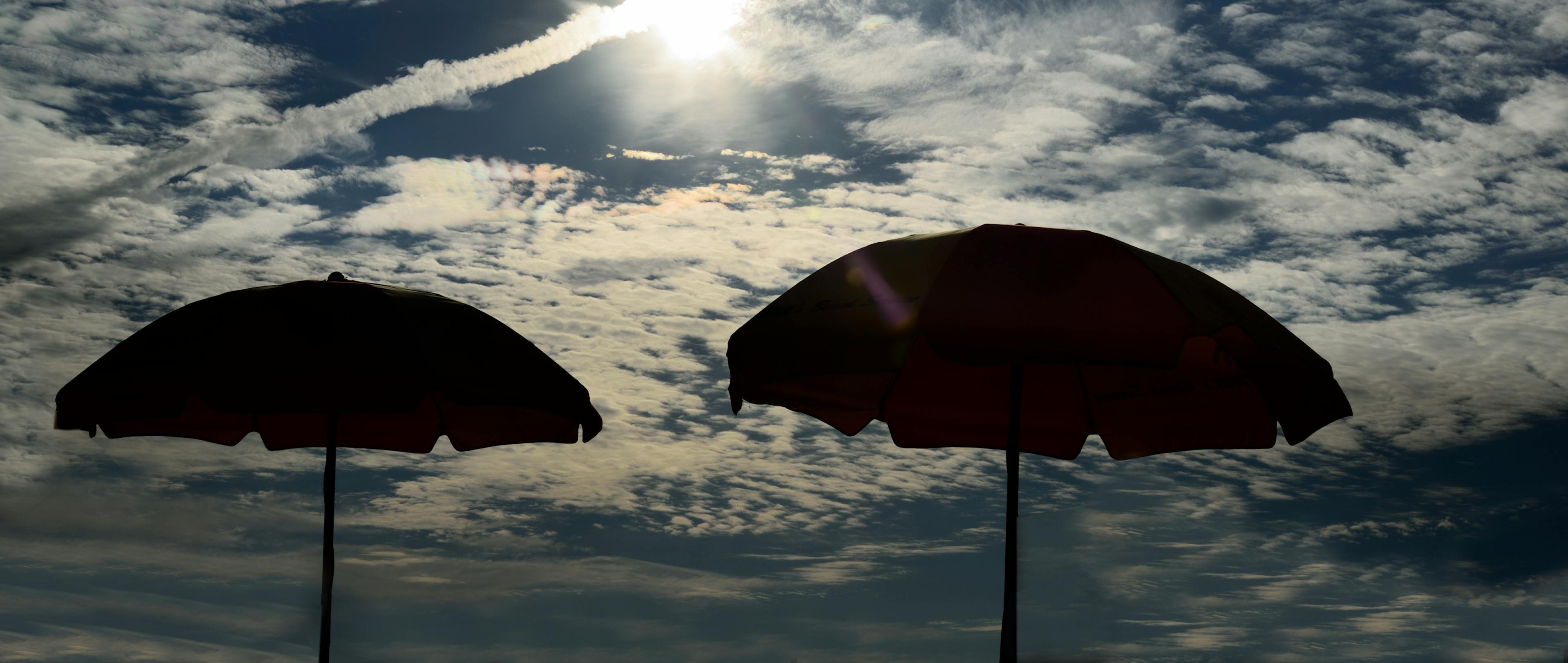 Two umbrellas are positioned under a brilliant sky.