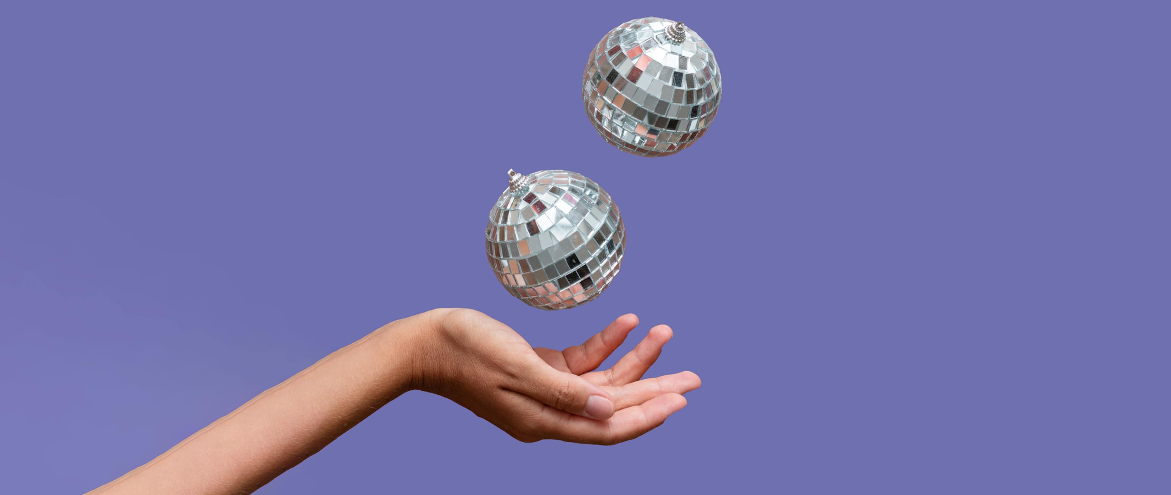 A hand juggling two disco balls