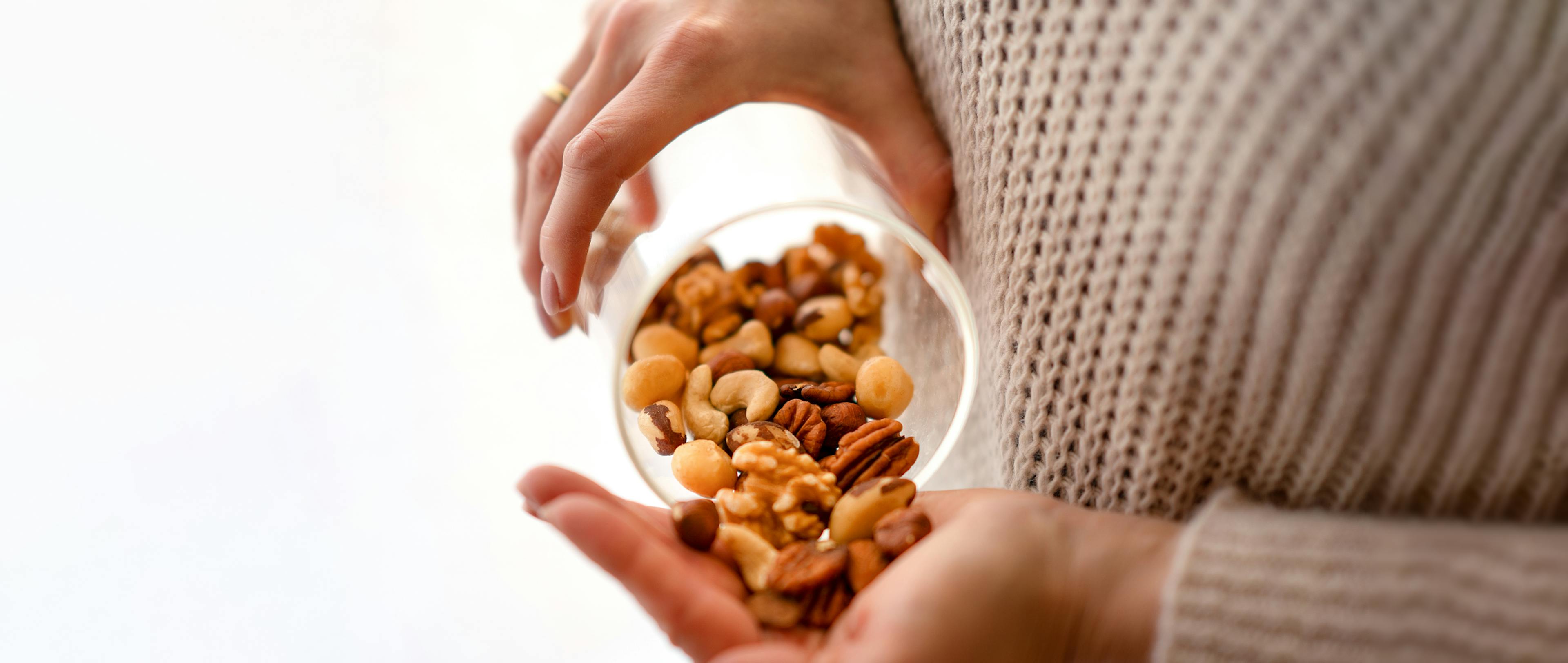 A woman taking out dry fruits from a transparent container.