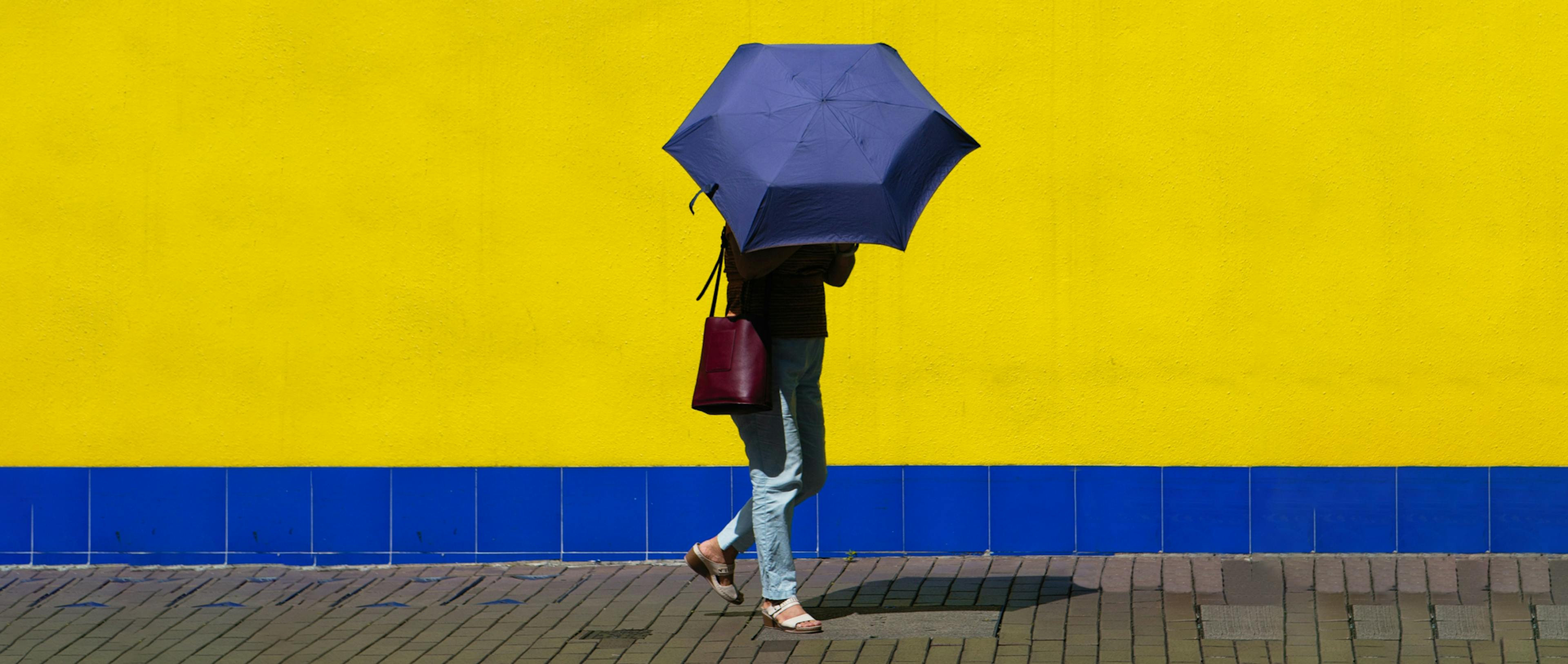 A person holding a blue umbrella as a shield from the sun. 