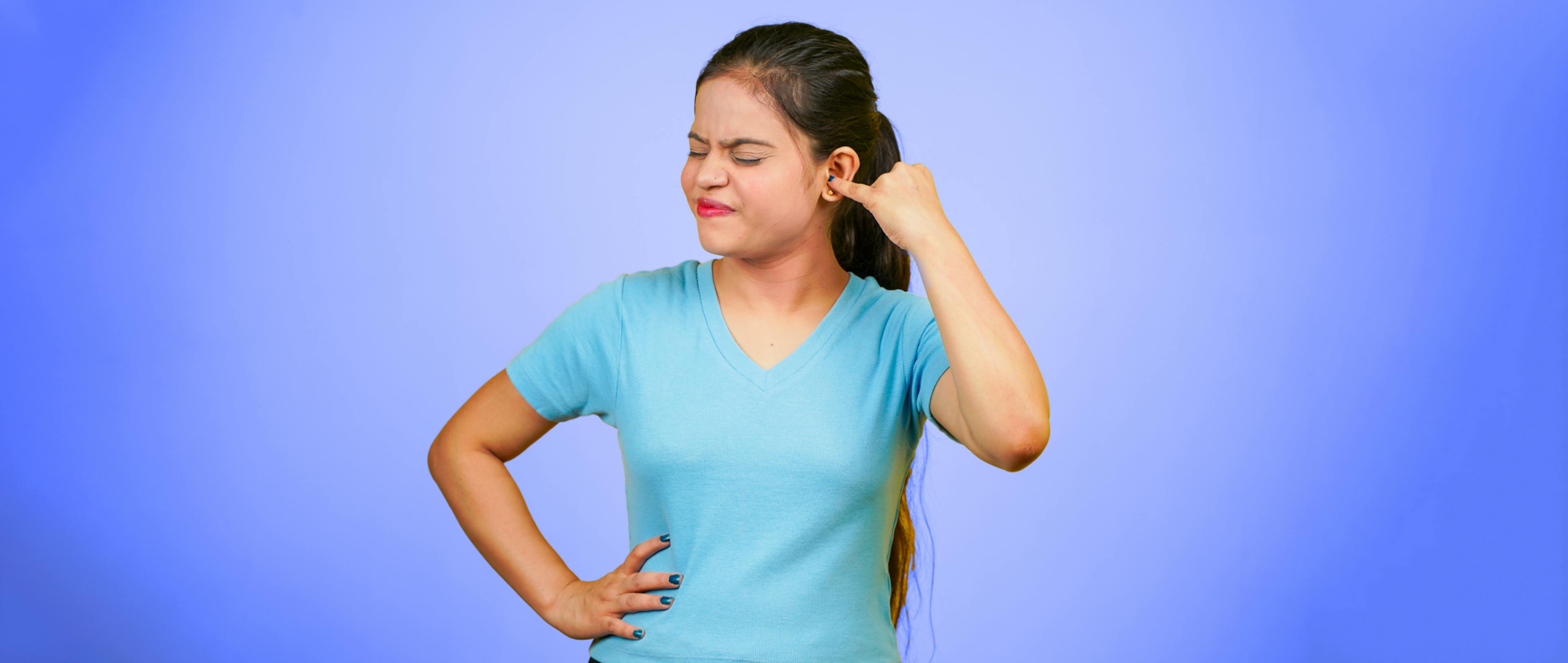 Young woman putting a finger into her ear,