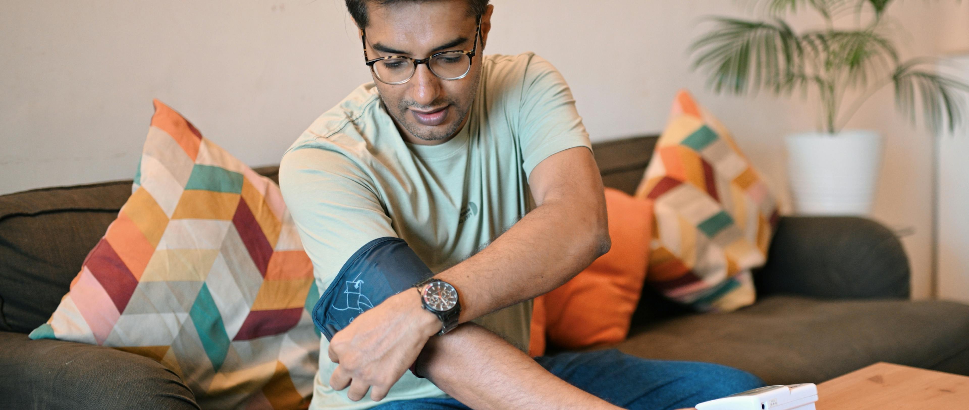 Man using Digital blood pressure monitor to check his blood pressure at home