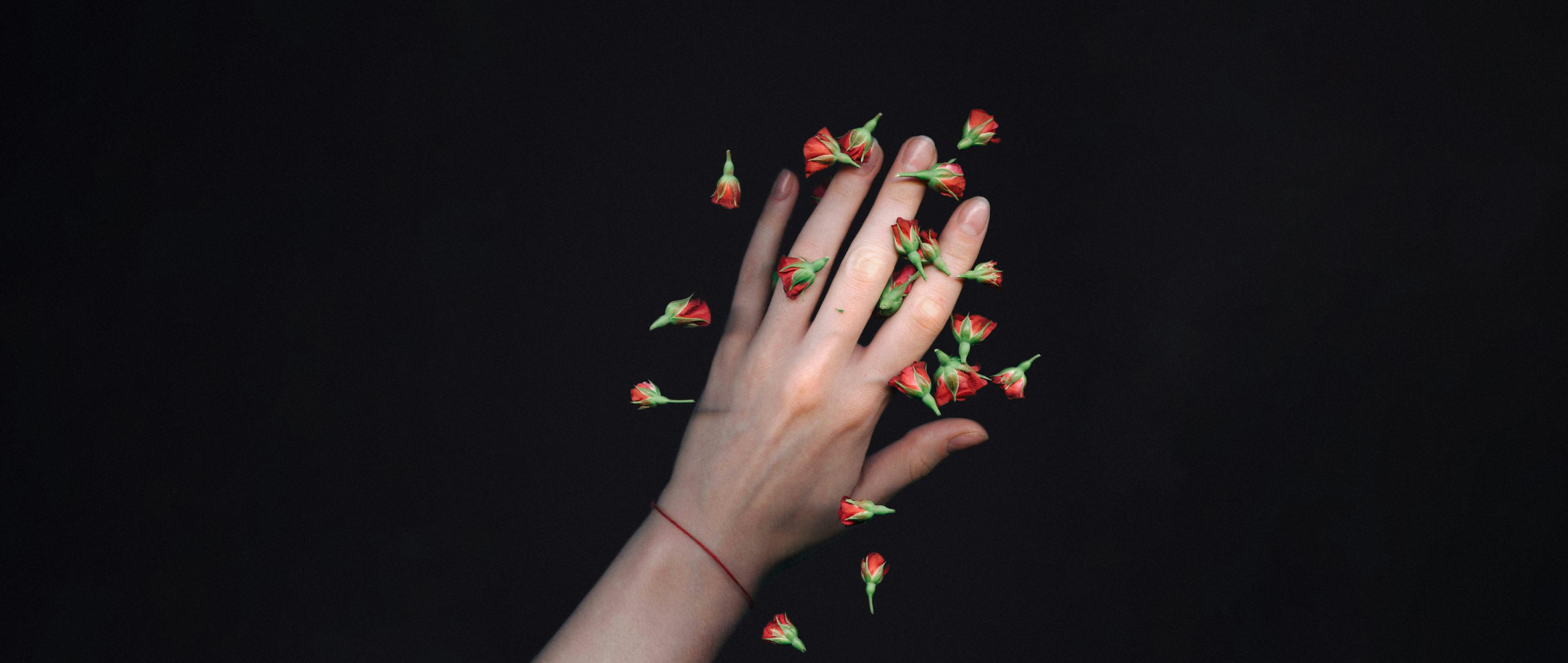 A person's left hand with red flowers.