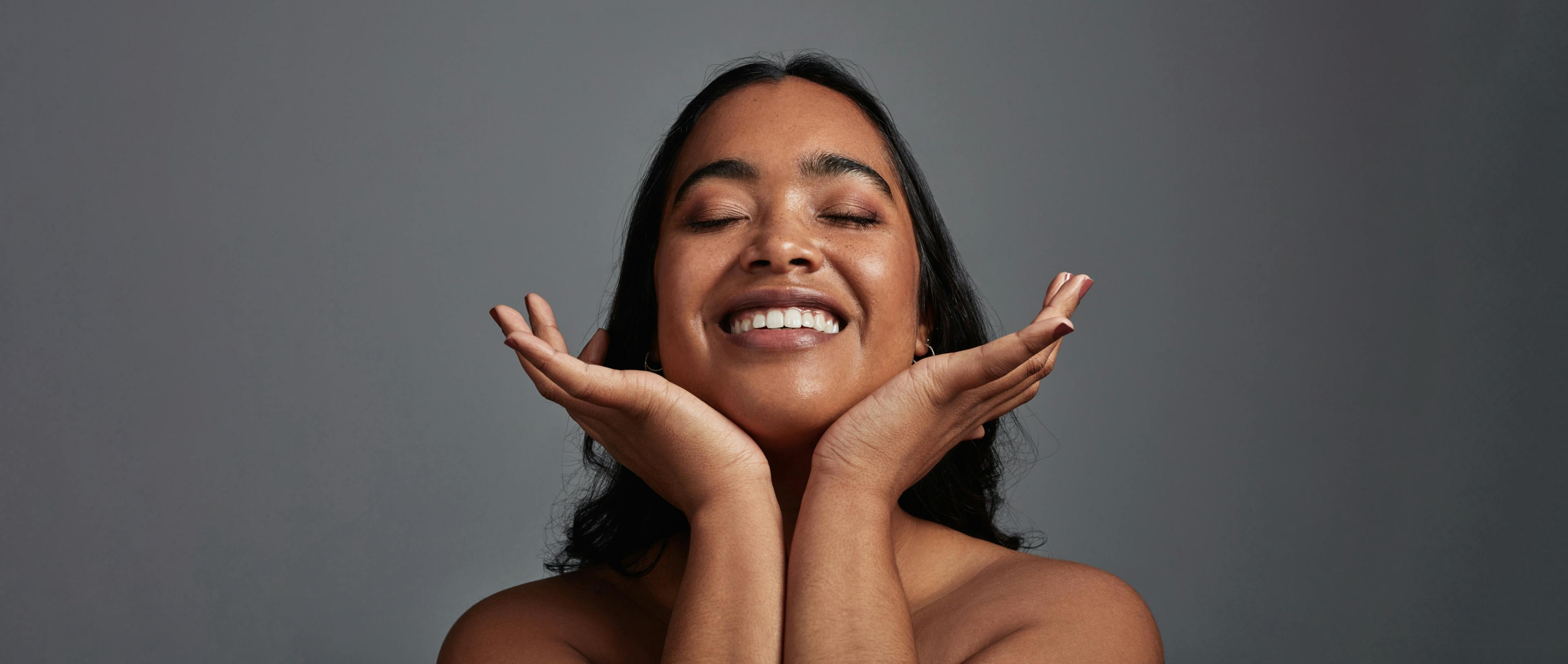 A beautiful young woman posing against a grey background.