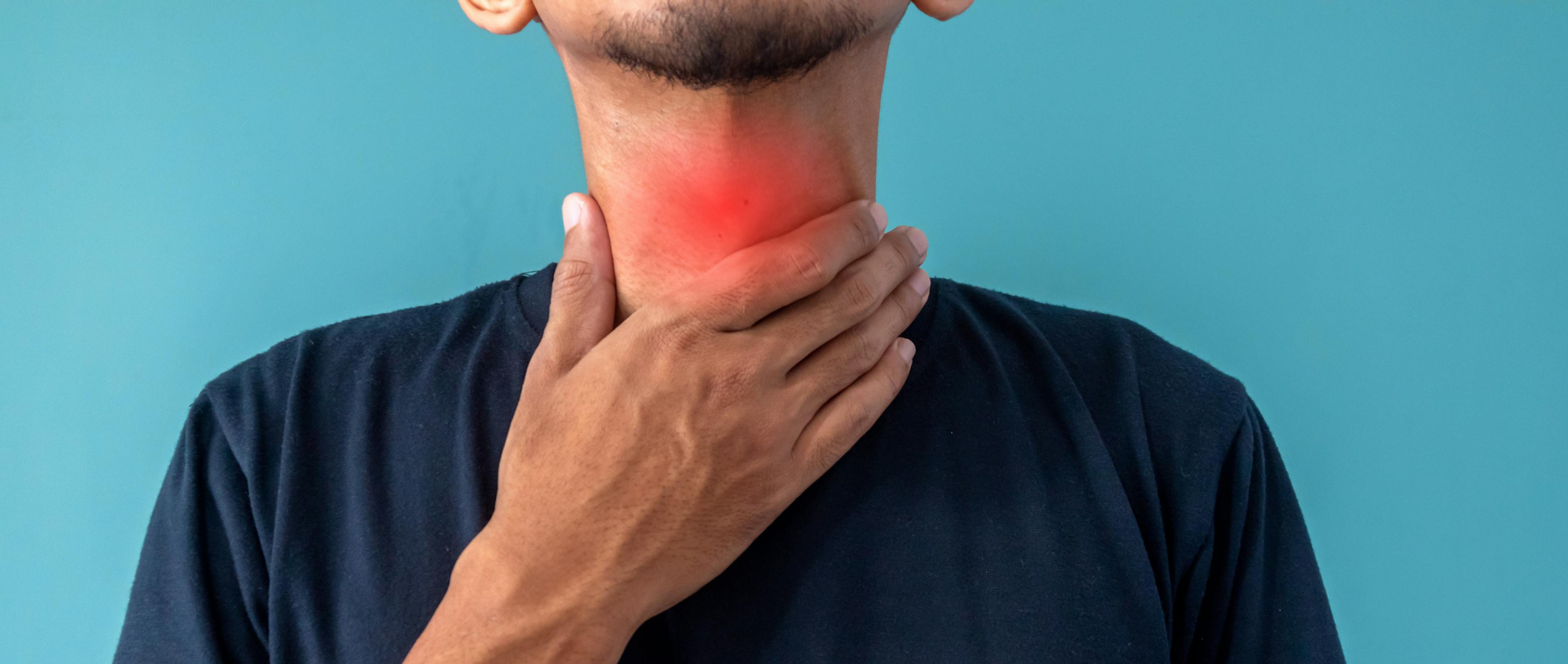 A man has sore throat and touches his throat.