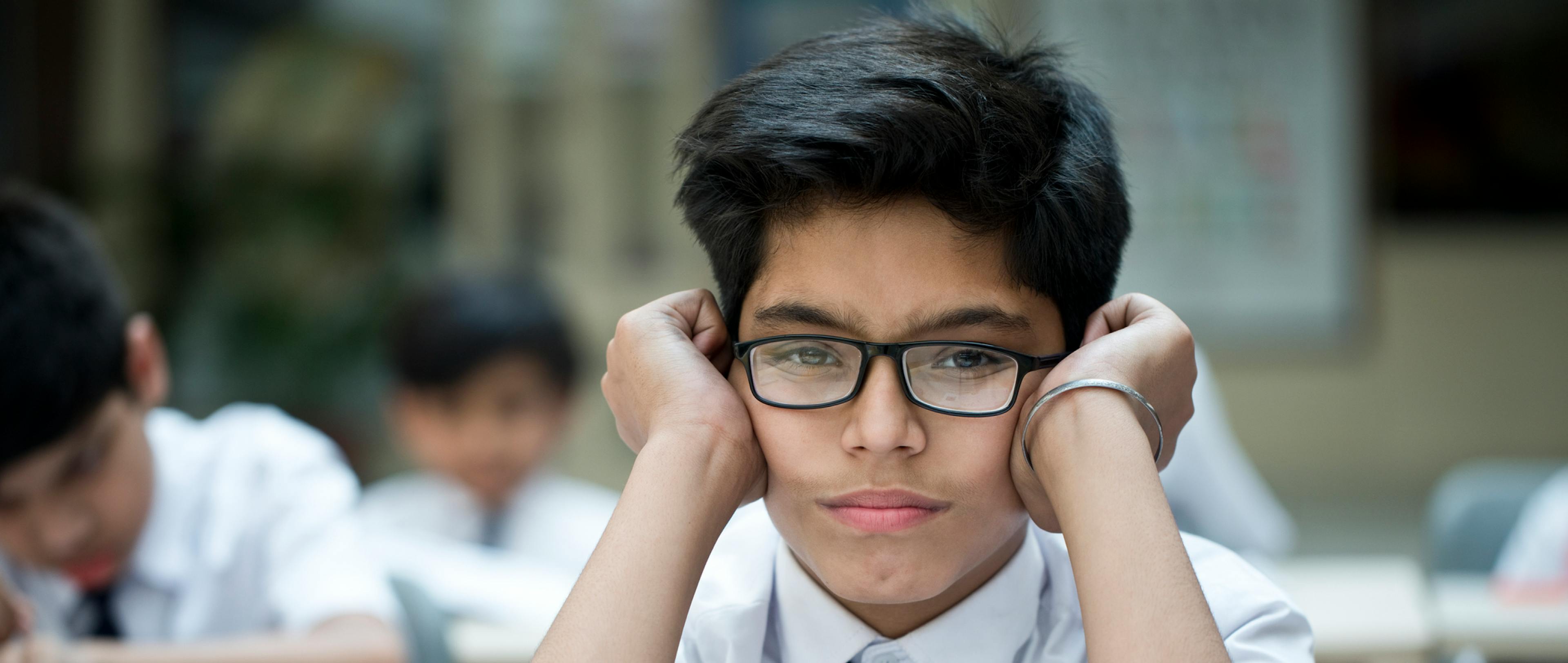 A boy sitting in school looking upset or pensive