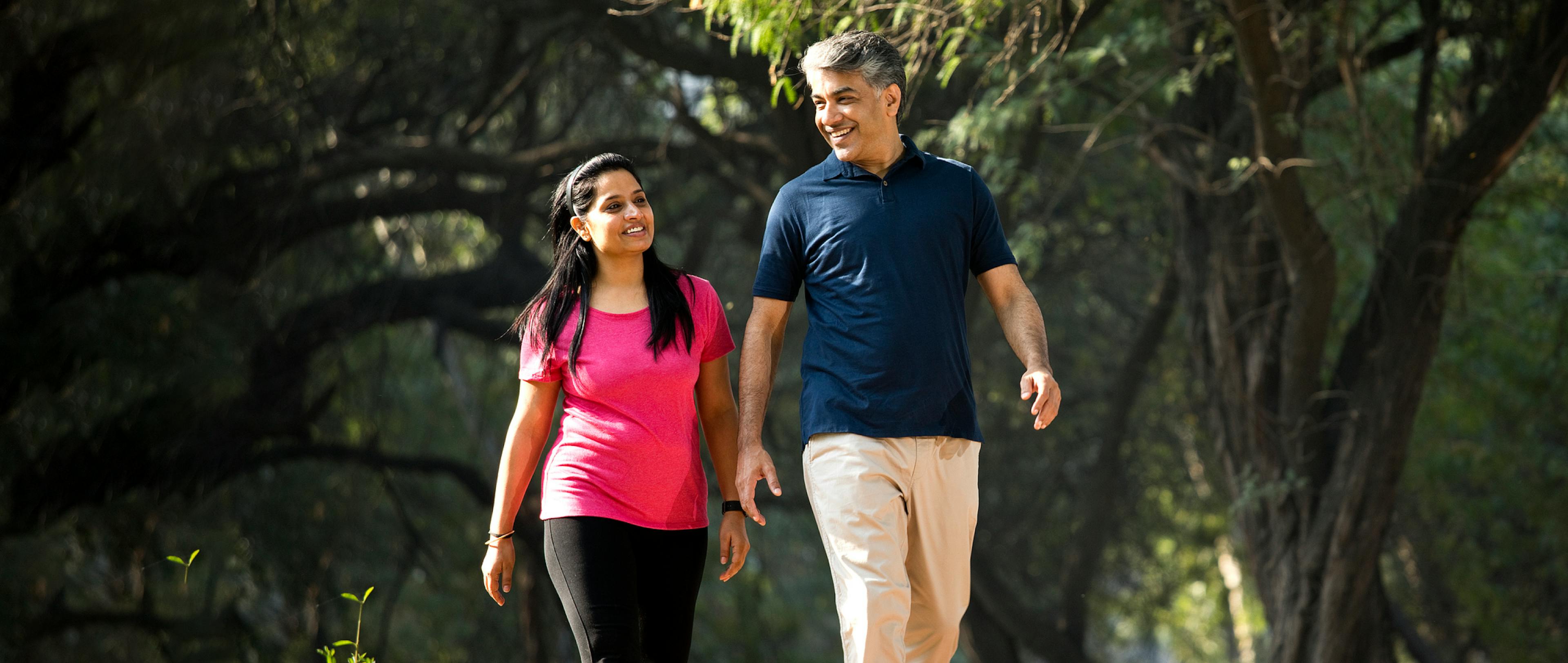 A couple walking in a park with greenery. 