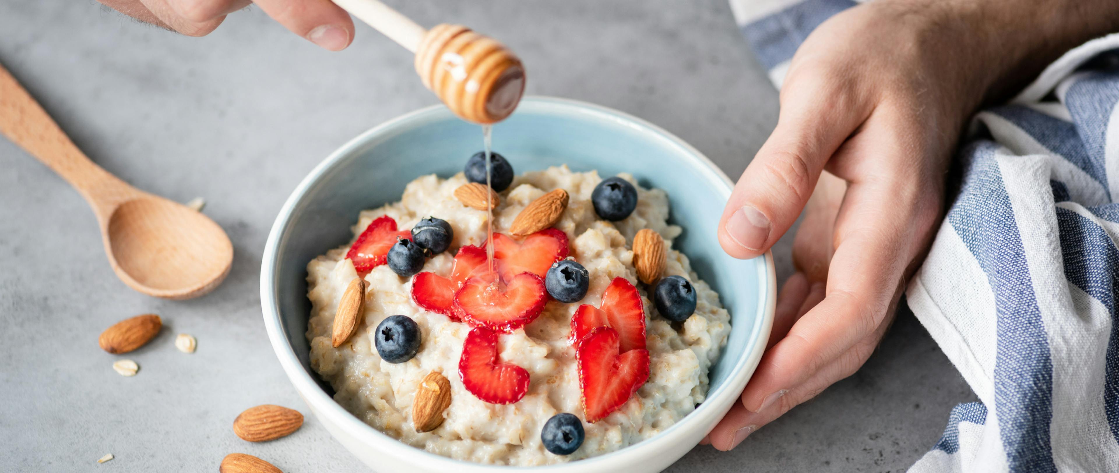 Eating healthy breakfast oatmeal porridge with fresh berries and nuts. Healthy lifestyle