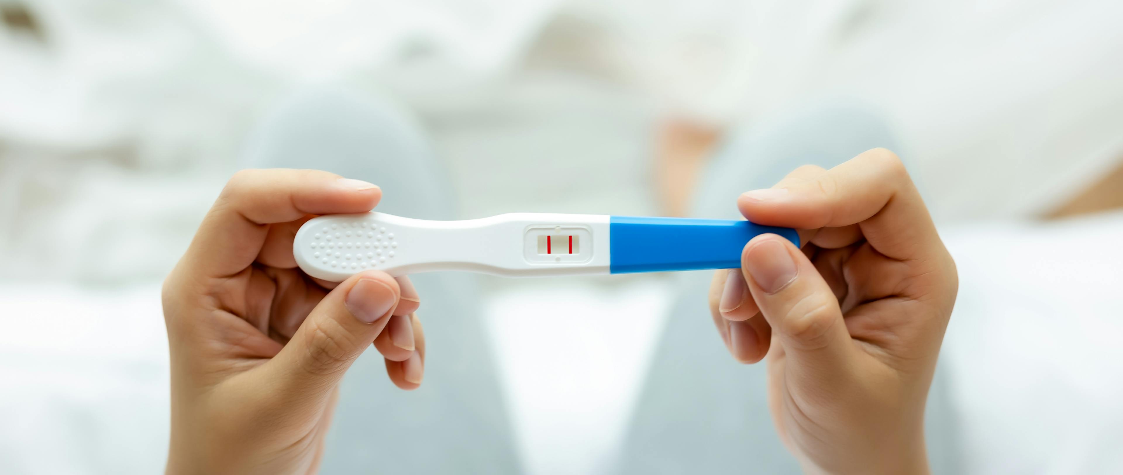 Pregnant woman holding pregnancy test, examine positive test.