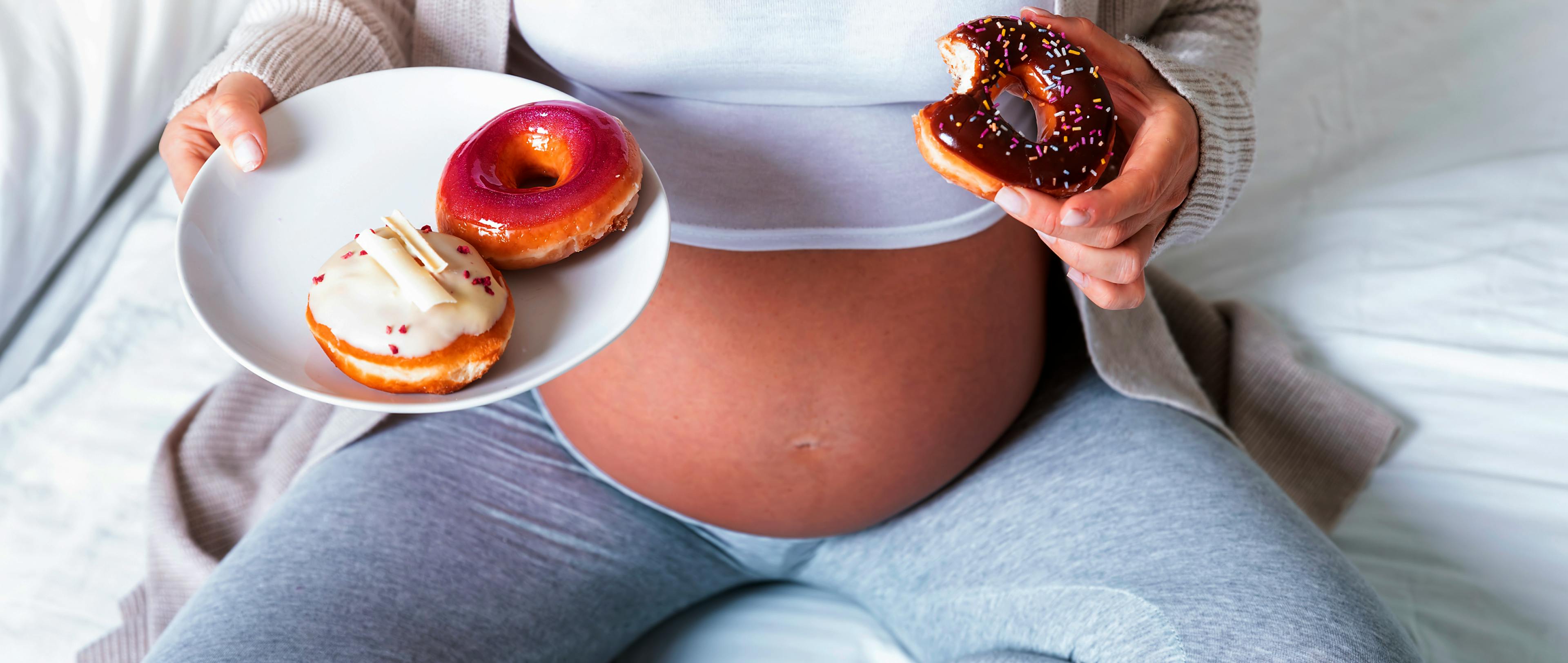 a pregnant woman eating donuts