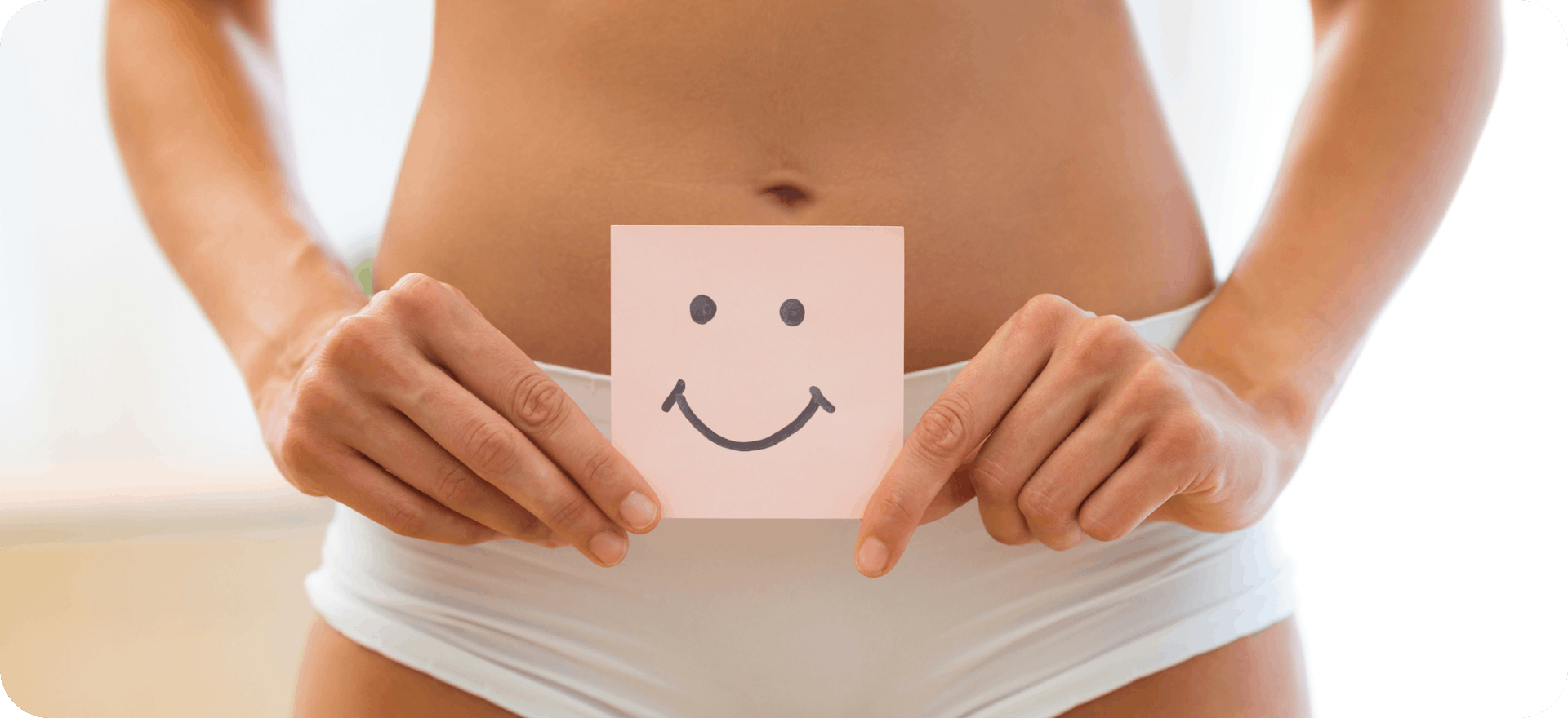 A woman holding a smiley picture, representing preventative measures for urinary tract infections (UTIs) and a happy urethra
