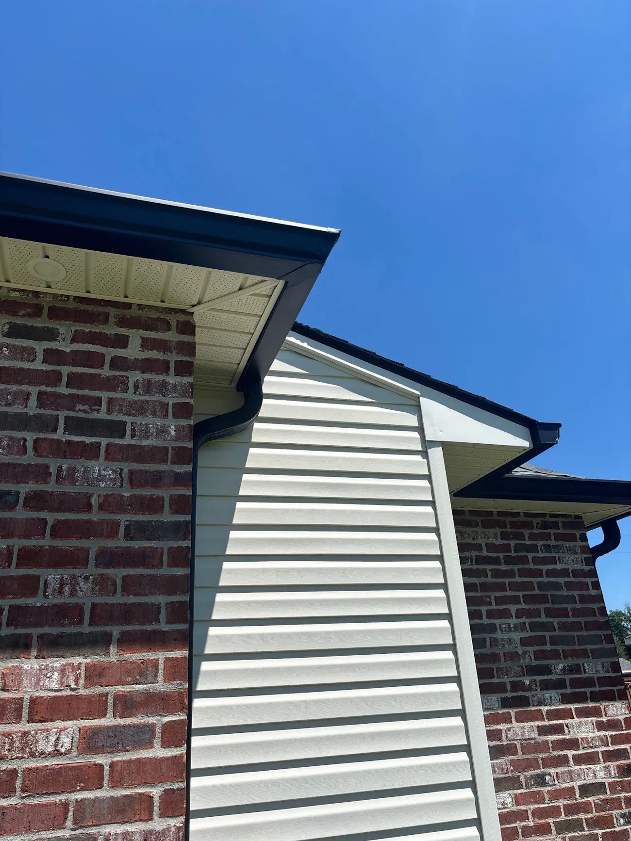 vinyl siding installation and black seamless gutter replacement on residential brick home - Boise, ID - Flux Boise Roofing & Siding