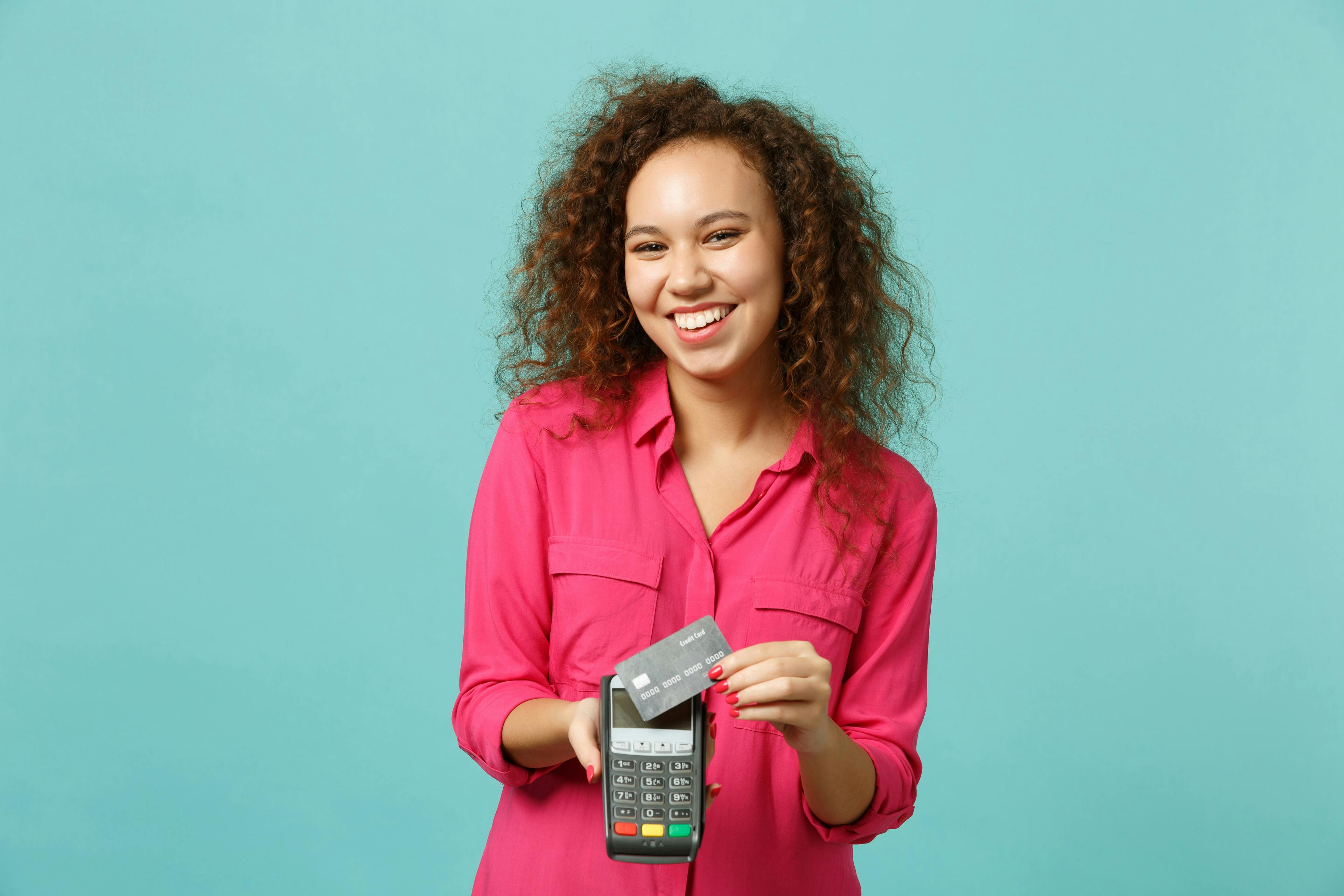 joyful girl holding wireless modern bank payment terminal