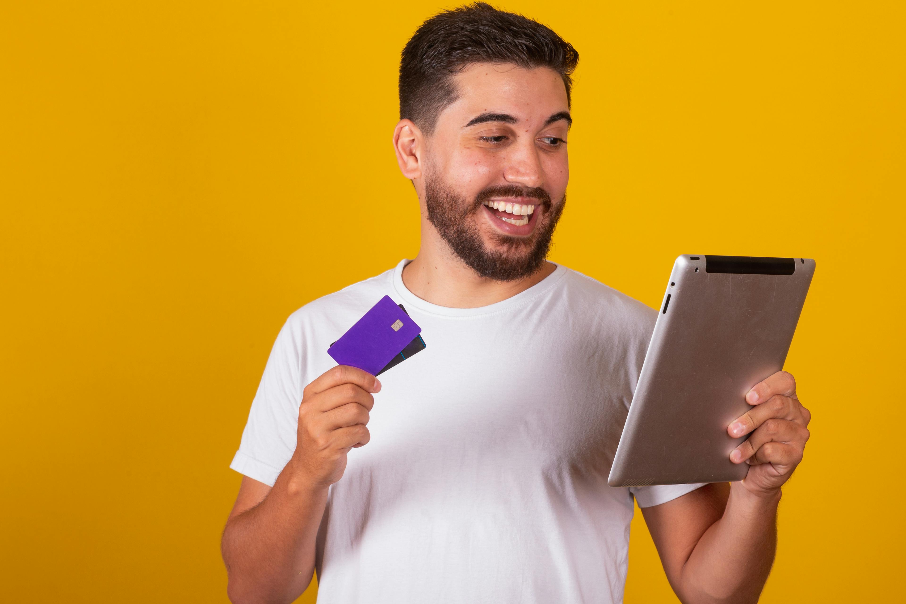 man holding credit card looking at ipad