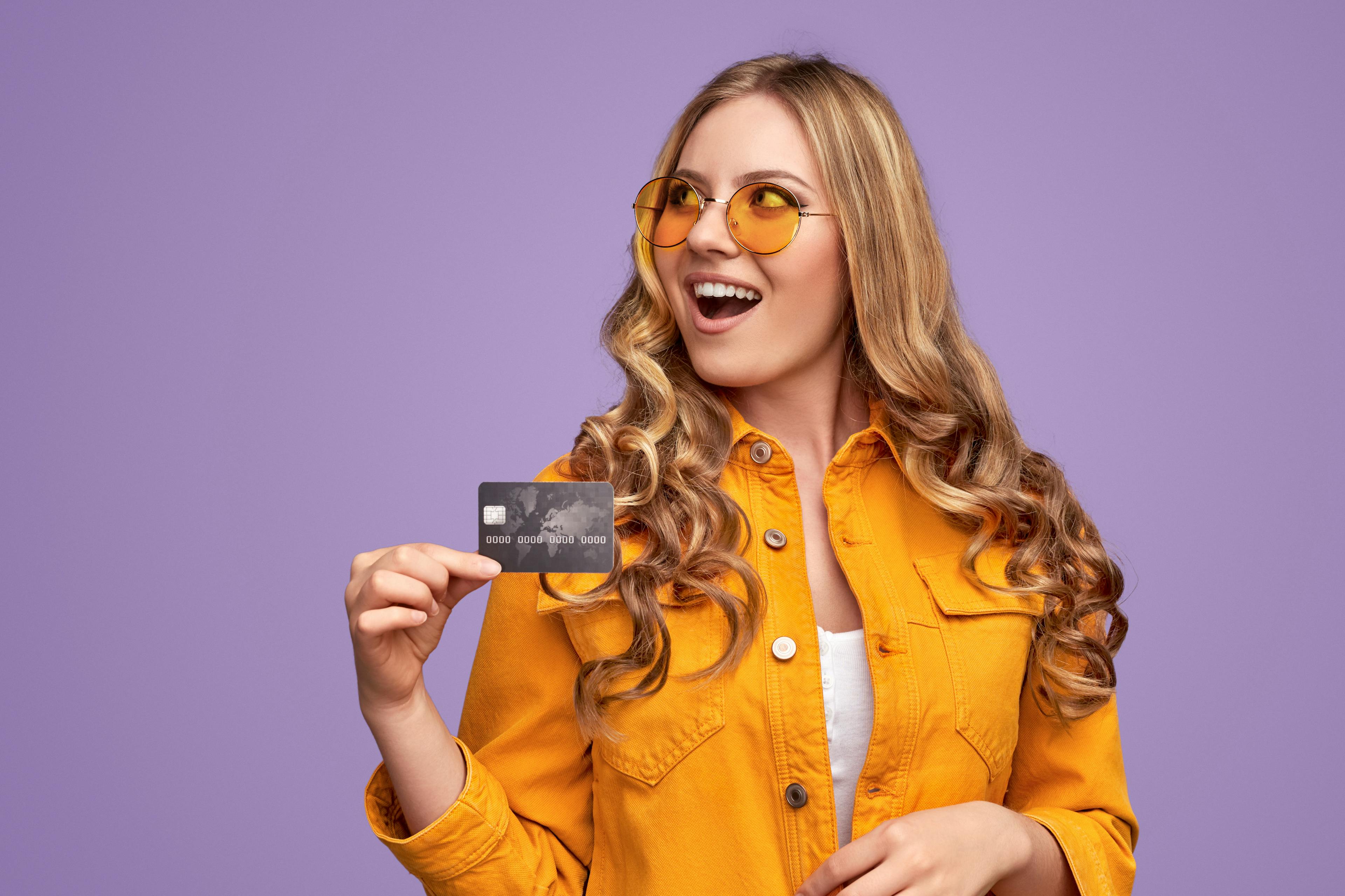 woman in yellow jacket holding credit card