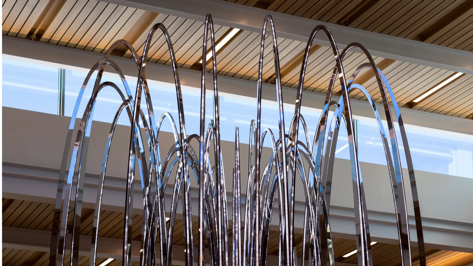 Close-up view of tall, reflective metal loops forming a sculptural canopy at Kansas City International Airport.
