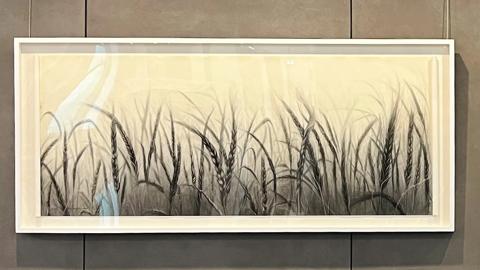 Framed monochrome artwork depicting tall wheat stalks in a softly fading gradient from dark at the base to light at the top, evoking a misty prairie field.