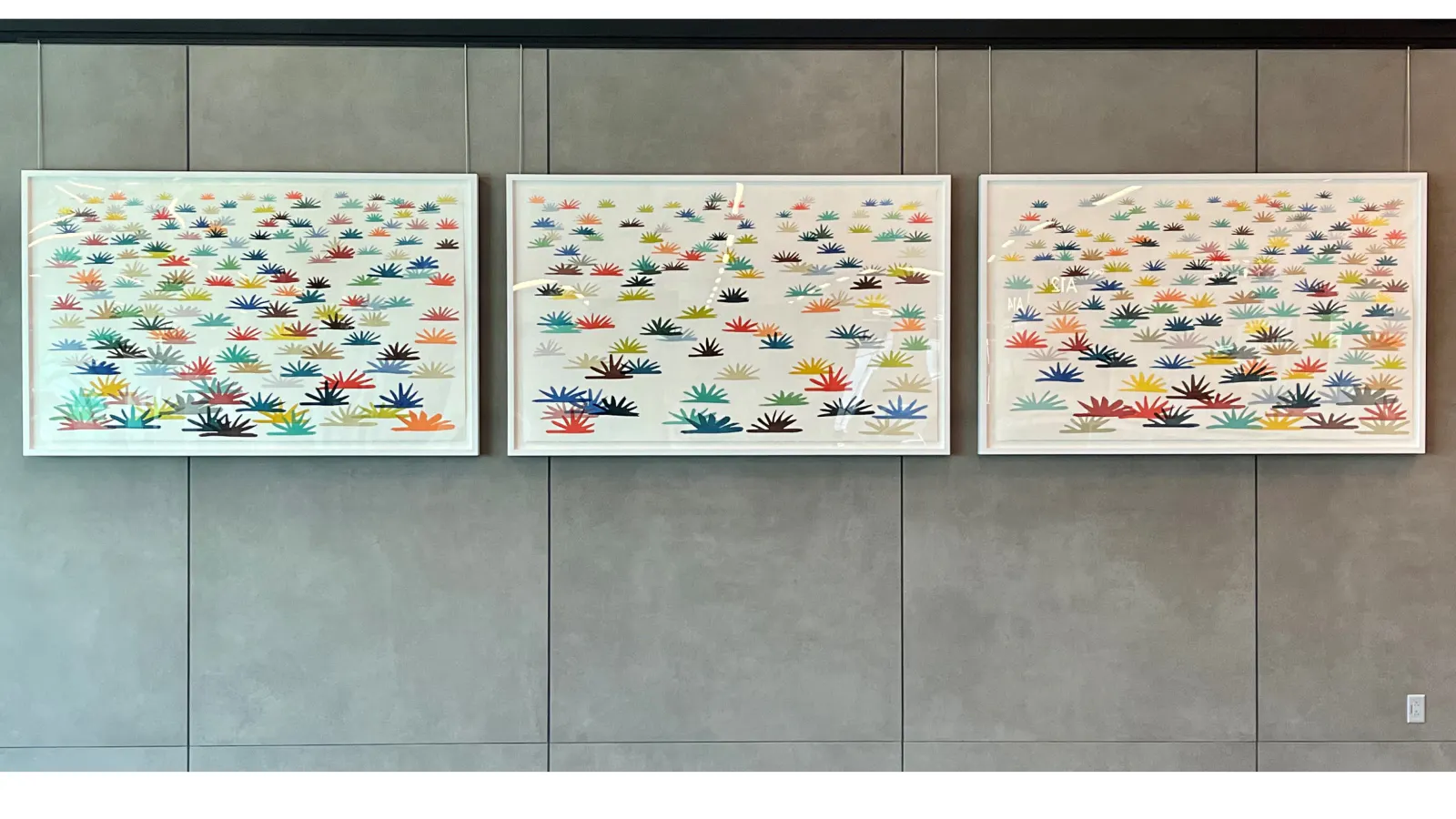 Large mural composed of hundreds of colorful, abstract plant-like forms evenly spaced across a white background, creating a vibrant, rhythmic pattern.