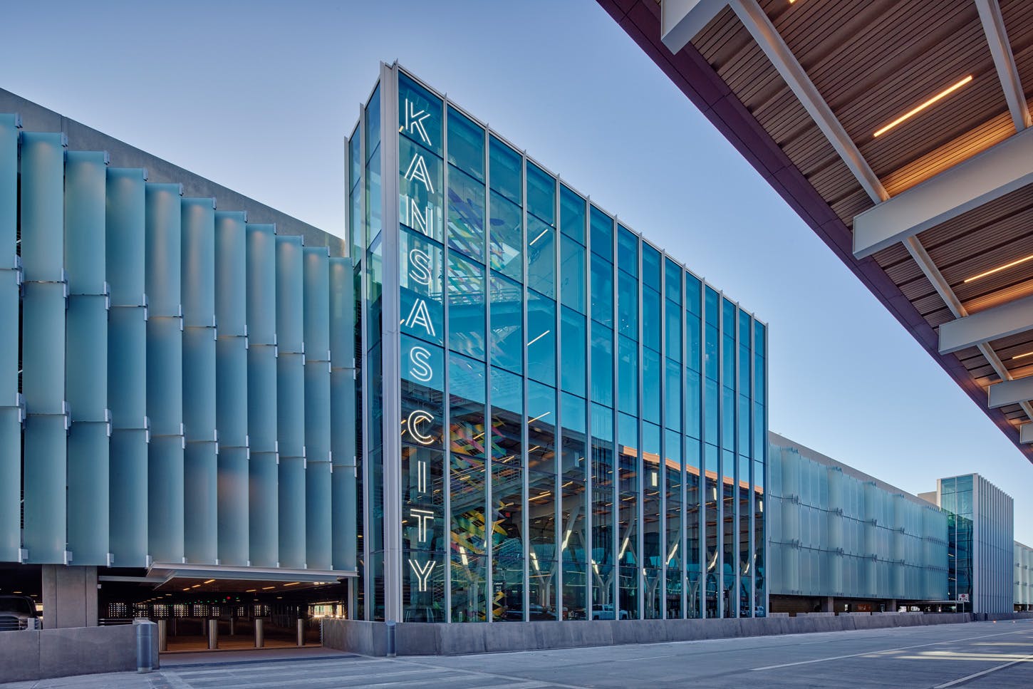 Multi-level parking garage with open sides and ramps, seen from below against a blue sky.